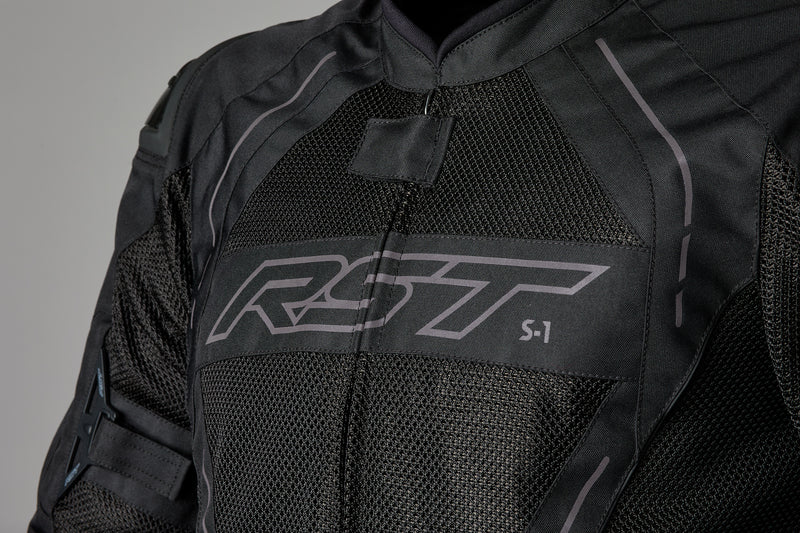 Framdetalj av RST Textil Mc-Jacka S-1 Mesh Svart med logotyp och ventilerande meshmaterial för maximal luftflöde och komfort.